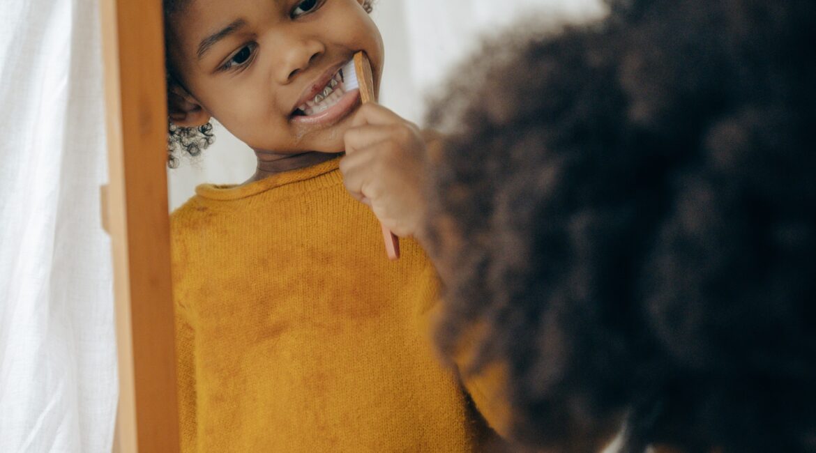 child brushing teeth in the mirror